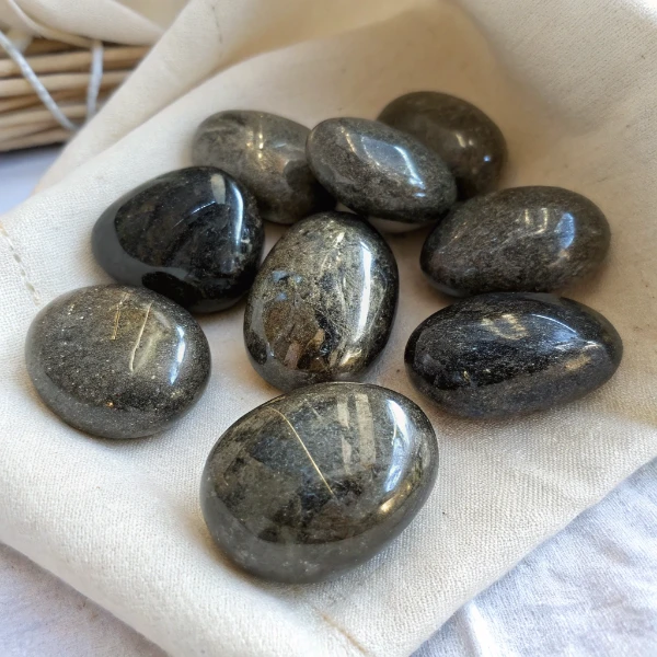 Nephrite Jade Stones Closeup Natural nuummite stone from Greenland showing golden and blue iridescent flash against black background