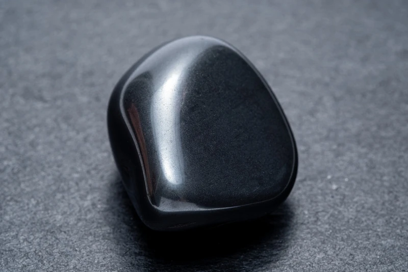 Polished tumbled obsidian stones showing smooth glossy black surface and natural variations
